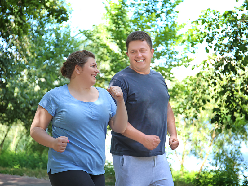 Overweight couple running in green park