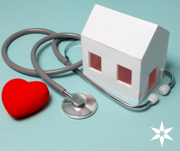 Picture of a model house with a stethoscope and a red heart on a blue background.