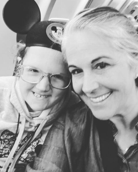 A black and white photograph of Susan and Genevieve sitting closely. Genevieve is wearing Mickey Mouse ears.