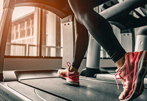 Close up of a woman on treadmill focusing on her legs and running shoes