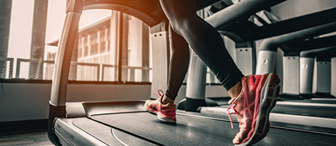 Close up of a woman on treadmill focusing on her legs and running shoes